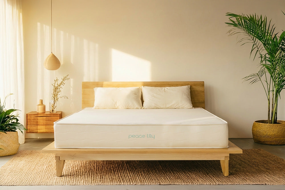 Peace Lily latex mattress on a natural wooden bed frame in a warm, sunlit bedroom