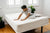 Person fitting a corner of an organic cotton mattress protector on a bed